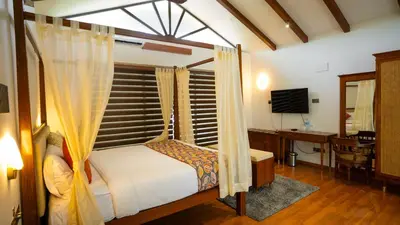 a bedroom with a bed and a desk and a television at Sakthi River Resort in Pollāchi