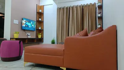 a living room with a couch and a tv at Eve Service apartment in Mysore