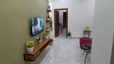 a living room with a tv on a wall with potted plants at Eve Service apartment in Mysore