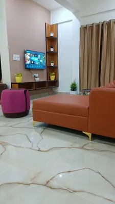 a living room with a couch and a flat screen tv at Eve Service apartment in Mysore