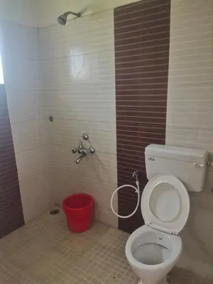 a bathroom with a toilet and a red bucket at Ooty mountain Cottage in Ooty