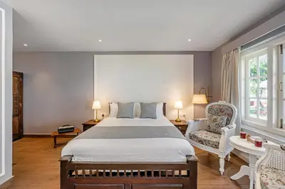 a bedroom with a large bed and a chair at Tiverton Bungalow in Ooty