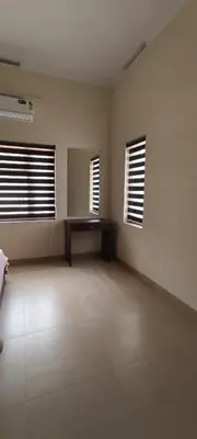 a large empty room with two windows and a table at Aura Villa in Kozhikode