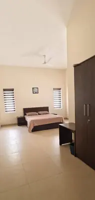 a bedroom with a bed and two windows at Aura Villa in Kozhikode