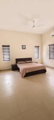 a bedroom with a bed and two windows at Aura Villa in Kozhikode