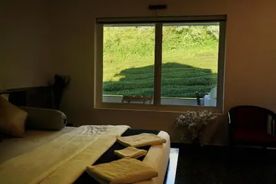 a bedroom with a bed and a window with a view at Green Leaves The Countryside Inn in Ooty