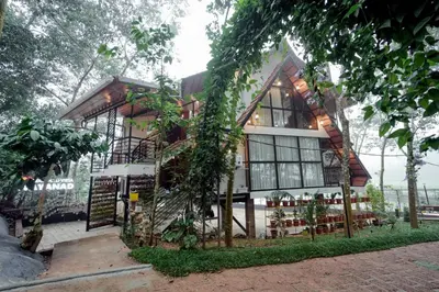 a house with a lot of windows and trees at Wayanad Vista Palm View Homes in Padinjarathara