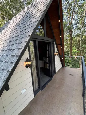a screened in porch of a house with a roof at Cicadas Nature Resort - A Frame cottages in Wayanad