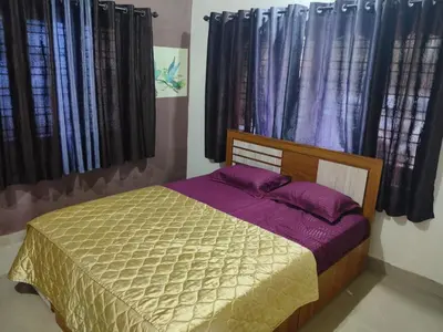 a bedroom with a bed with purple sheets and windows at Wild mist in Padinjarathara