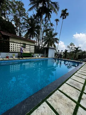 a swimming pool at a resort with people walking around it at Wild mist in Padinjarathara