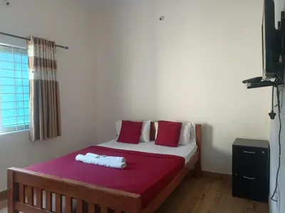 a bedroom with a bed with red and white pillows at MM comforts in Mysore