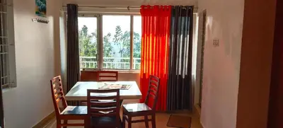 a dining room with a table and chairs and a window at Dam Valley Home Stay Resort in Parambikolam