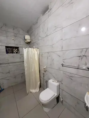 a white bathroom with a toilet and a shower at Akalapuzha Homestay in Kozhikode