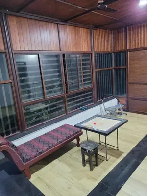 a room with a bench and a table and windows at Akalapuzha Homestay in Kozhikode