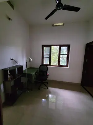 an empty room with a chair and a ceiling fan at Akalapuzha Homestay in Kozhikode