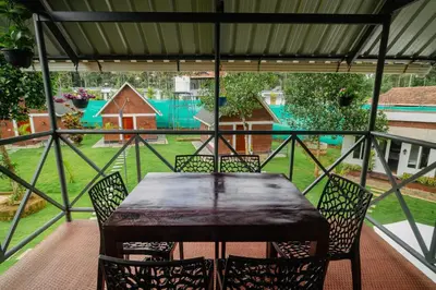 a table and chairs on a porch with a view of a yard at Misty Forest Resort Wayanad in Wayanad