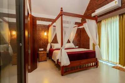 a bedroom with a canopy bed with a red blanket at Misty Forest Resort Wayanad in Wayanad