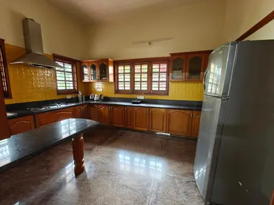 a kitchen with wooden cabinets and a stainless steel refrigerator at 6bhk Luxury Villa in Mysore