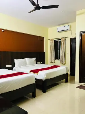 a bedroom with two beds and a ceiling fan at Avini Stay in Mysore