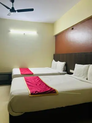 two beds in a hotel room with red sheets at Avini Stay in Mysore