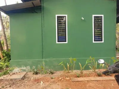 a green building with two windows on the side of it at Farmville Riverside in Kakkayam