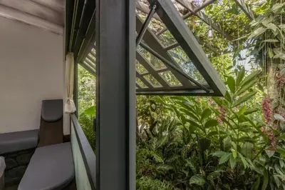 a glass door leading into a room with plants at Malhar - Your Home Beneath The Clouds in Sultan Bathery