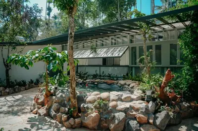 a swimming pool in front of a building with trees at Malhar - Your Home Beneath The Clouds in Sultan Bathery