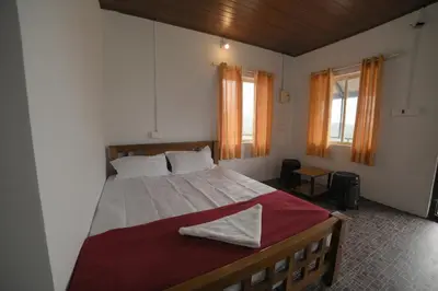 a bedroom with a large bed and two windows at Drizzling Home Stay in Vattavada