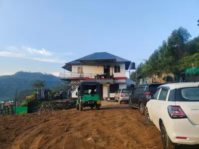 a dirt road with cars parked in front of a house at Drizzling Home Stay in Vattavada