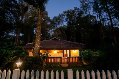 a house with a white fence in front of it at Yaala - Coorg Riverside Retreat in Napoklu