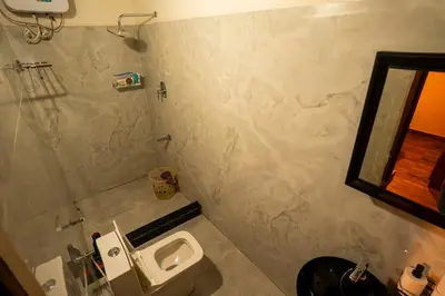 a bathroom with a toilet and a sink and a mirror at Yaala - Coorg Riverside Retreat in Napoklu