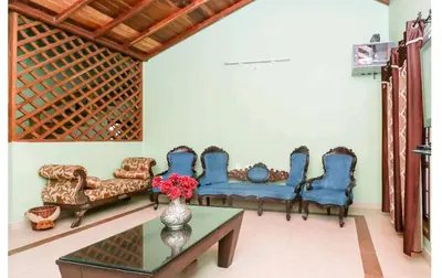a living room with blue chairs and a table at Deep view luxury villa Coffee Cottage Coorg in Madikeri