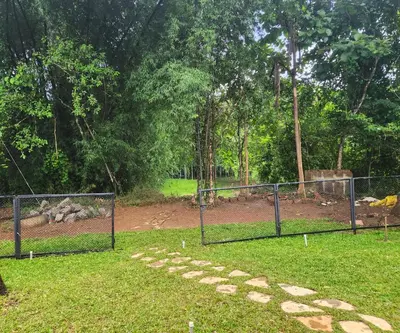 a chain link fence in a park with a field at RiverMist Resort in Nilambūr