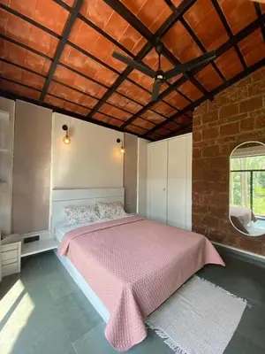 a bedroom with a pink bed and a brick wall at RiverMist Resort in Nilambūr