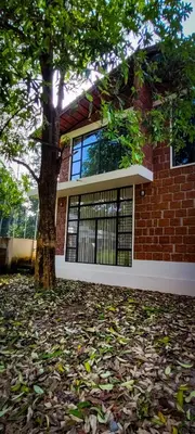 a brick house with a tree in front of it at RiverMist Resort in Nilambūr