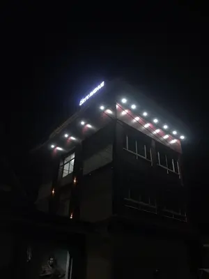 a lit up building with a sign on top at night at low budget room at Kalpetta in Kalpetta