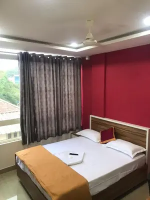 a bedroom with a bed with a red wall at low budget room at Kalpetta in Kalpetta