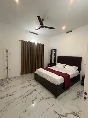 a bedroom with a bed and a ceiling fan at Homie Hub in Meppādi