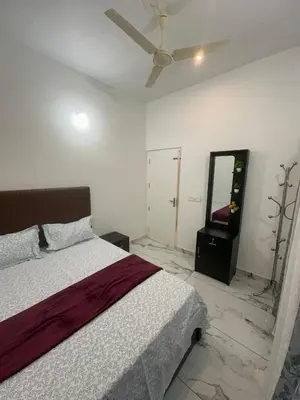a bedroom with a bed and a ceiling fan at Homie Hub in Meppādi