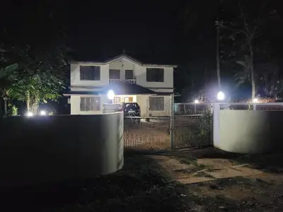 a white house with lights on a fence at night at Wayanad Villa homestay in Meenangadi