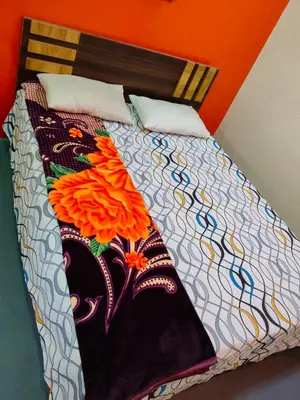a bed with a colorful comforter with flowers on it at Sri Vinayaka Tourist Home in Nanjangūd