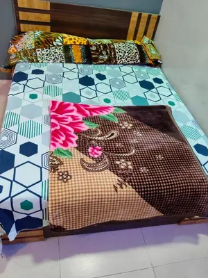 a bed with a colorful quilt on it at Sri Vinayaka Tourist Home in Nanjangūd
