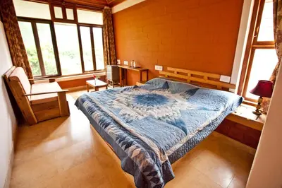 a bedroom with a bed and a chair and windows at Kabbe Hillview Homestay in Madikeri