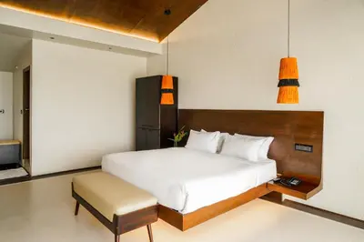 a bedroom with a large white bed and a stool at Virgin Valley Leisure Resort in Ooty