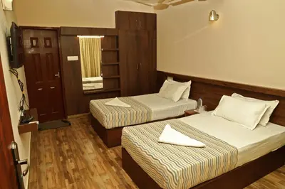 a hotel room with two beds and a mirror at Velu's Resort in Gūdalūr
