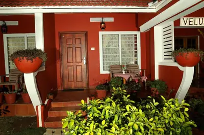 a red house with a red door and some plants at Velu's Resort in Gūdalūr