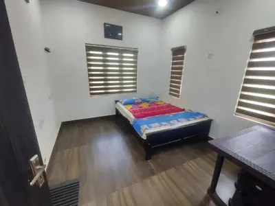 a bedroom with a bed in the corner of a room at Private Cottage Wayanad in Kalpetta