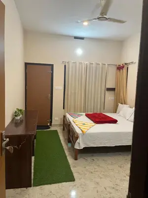 a bedroom with a bed and a desk and green rug at VARIYATH HOMESTAY THIRUNELLi in Thirunelli