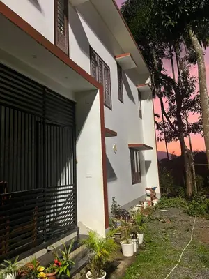 a building with a gate and plants on the side at VARIYATH HOMESTAY THIRUNELLi in Thirunelli