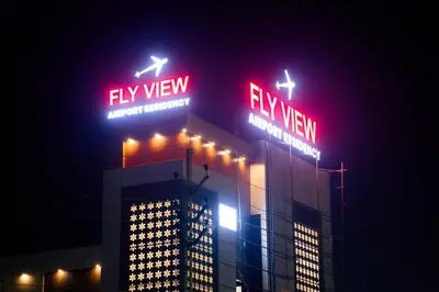a building with neon signs on top of it at night at FLY VIEW Airport Residency in Nedumbassery